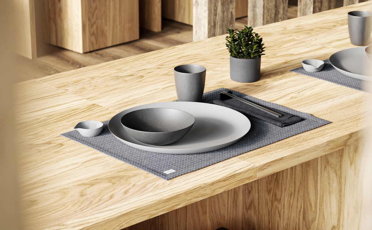 Modern dining table with minimalist tableware and potted plants.