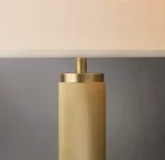Modern Gorvey lighting floor lamp with knurled gold finish under a table.