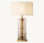 Elegant smoke glass table lamp with a beige lampshade and gold accents.
