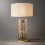 Elegant smoke glass table lamp with gold accents and a white lampshade.