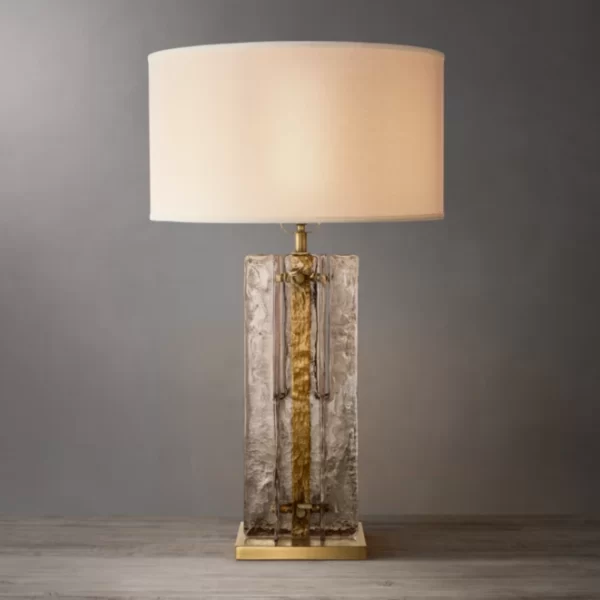 Elegant smoke glass table lamp with gold accents and a white lampshade.