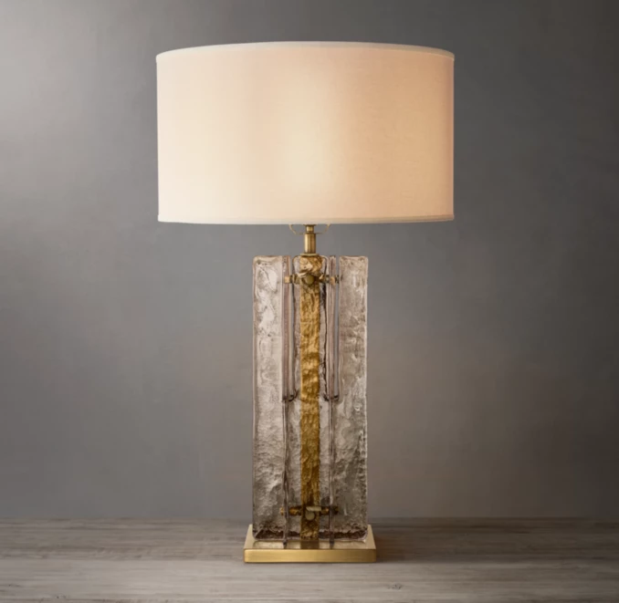 Elegant smoke glass table lamp with gold accents and a white lampshade.
