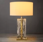 Elegant clear glass table lamp with a beige lampshade for modern decor.
