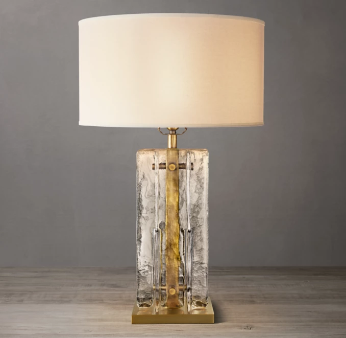 Elegant clear glass table lamp with brass accents and a white shade.