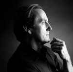 Black and white portrait of a thoughtful man with hand on chin.