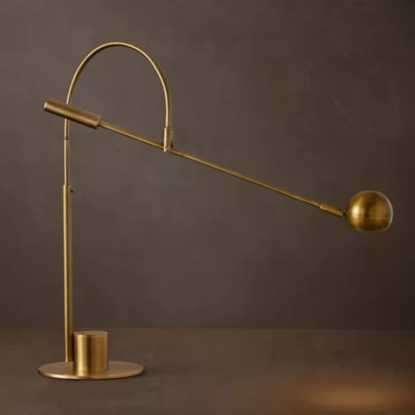 Brass task lamp with adjustable arm and spherical light for workspace illumination.