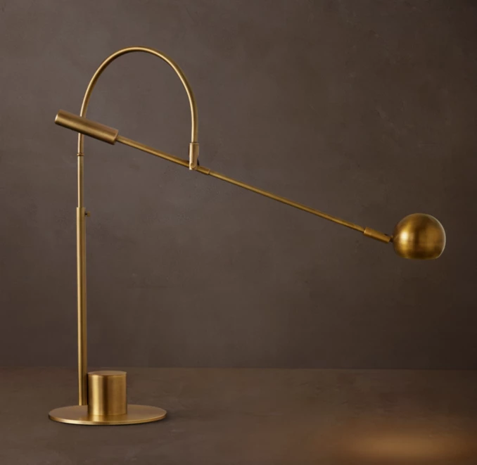 Brass task lamp with adjustable arm and spherical light for workspace illumination.