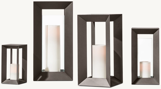Set of four modern candle holders with geometric black frames and white candles.