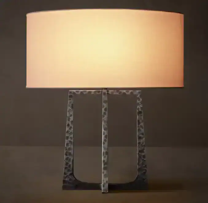 Contemporary table lamp with textured metal base and soft beige shade.