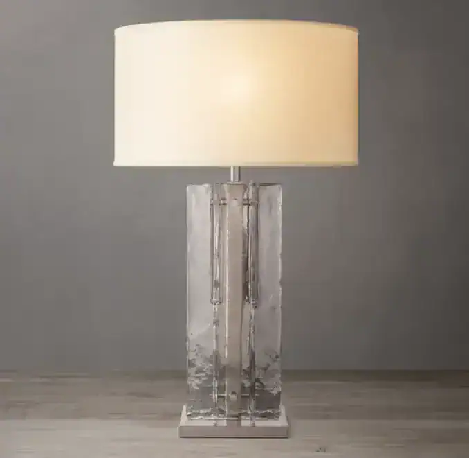 Elegant table lamp with glass base and cream lampshade for modern decor.