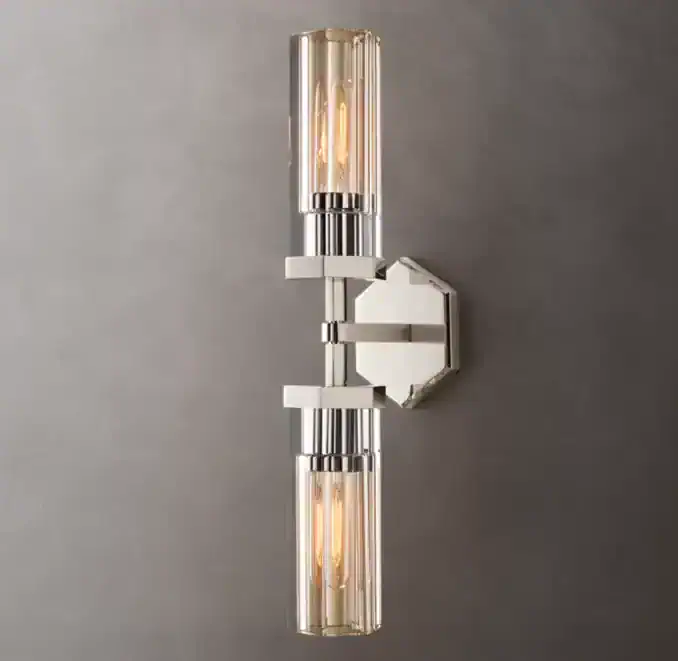 Contemporary wall sconce with dual glass tube lights and metallic finish.