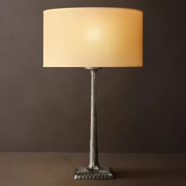 Forged metal lamp with beige lampshade on dark background.