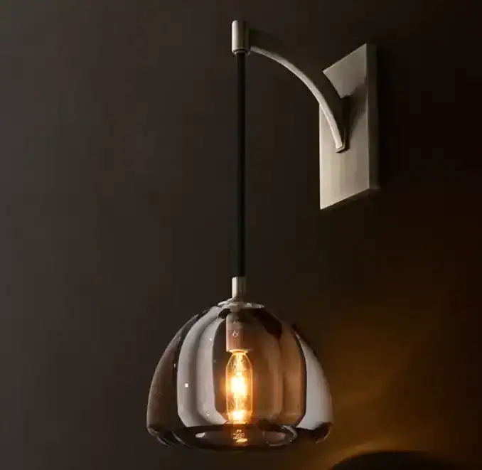 Modern glass sconce with brass finish and exposed filament bulb.