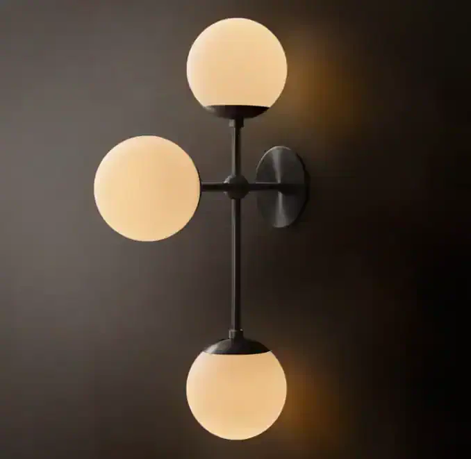 Modern wall sconce with three opal globe lights on black metal fixture.