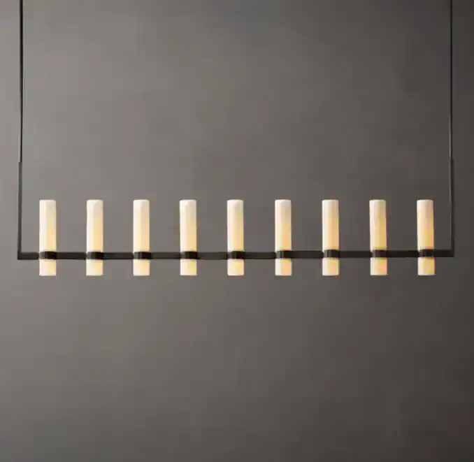 Modern linear glass chandelier with milk glass shades on a dark wall.