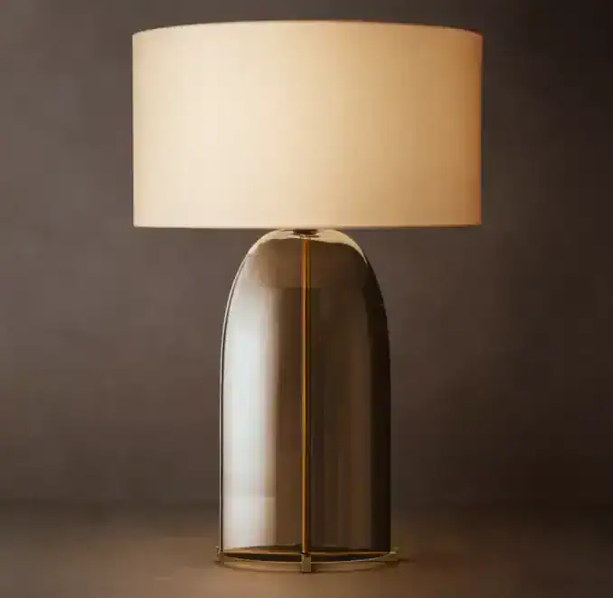 Amber glass table lamp with beige lampshade for modern decor.