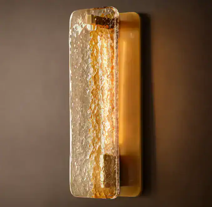 Modern glass and steel wall sconce with warm lighting for interior decor.