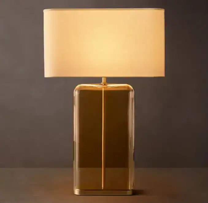 Amber rectangular glass table lamp with beige shade for modern decor.