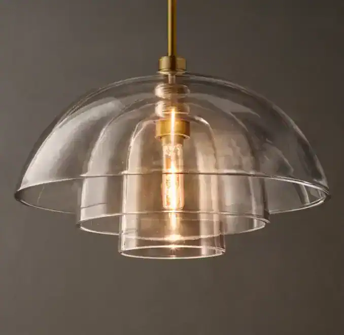 Modern glass cloche pendant light with warm glow, stylish lighting fixture for interiors.
