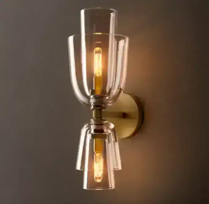 Elegant clear glass wall sconce with warm lighting for modern decor.