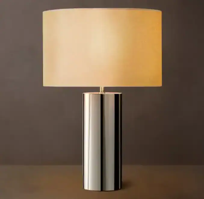 Modern brass cylindrical table lamp with beige lampshade for home decor.