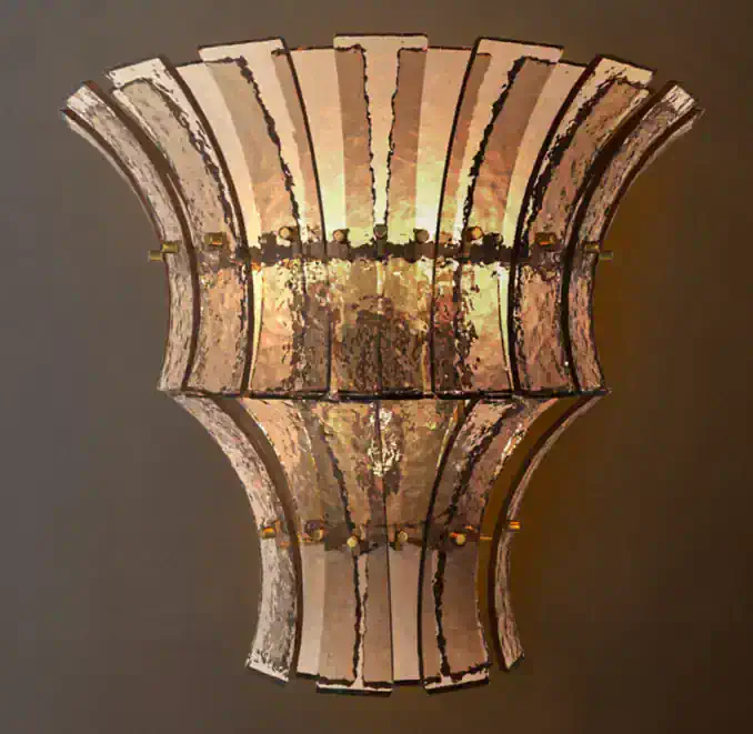 Vintage wall sconce with tiered textured panels and warm lighting.