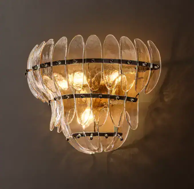 Elegant glass tiered sconce with warm lighting for sophisticated decor.