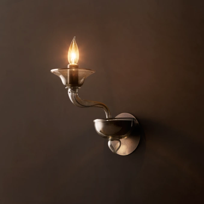 Modern glass wall sconce with exposed bulb for elegant lighting.
