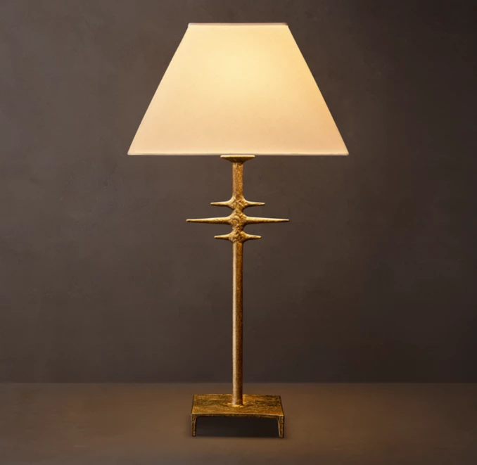 Modern metal table lamp with a beige lampshade and gold finish base.