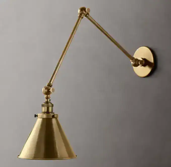 Brass wall sconce with adjustable arm and cone-shaped shade for classic lighting.