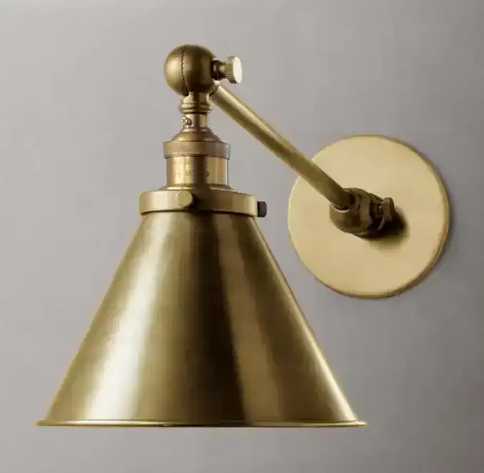 Vintage brass wall sconce with adjustable arm and conical shade for library lighting.